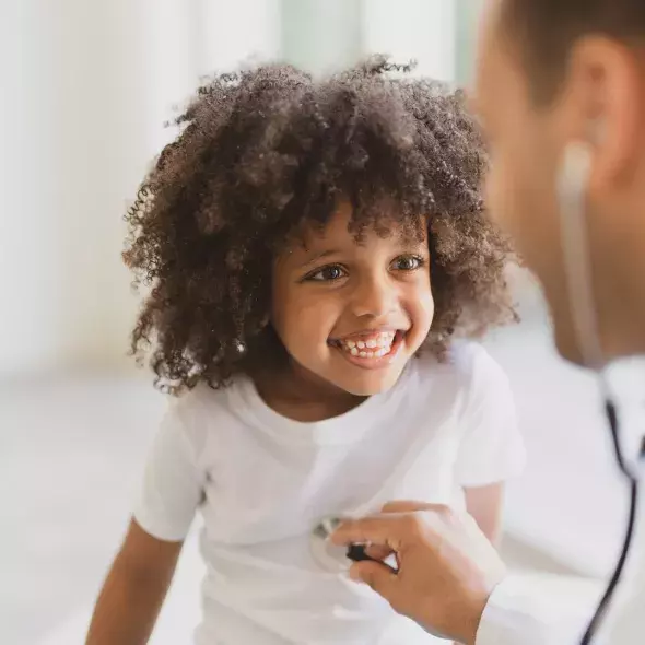 Doctor Listening to the Heartbeat of a Smiling Young Child