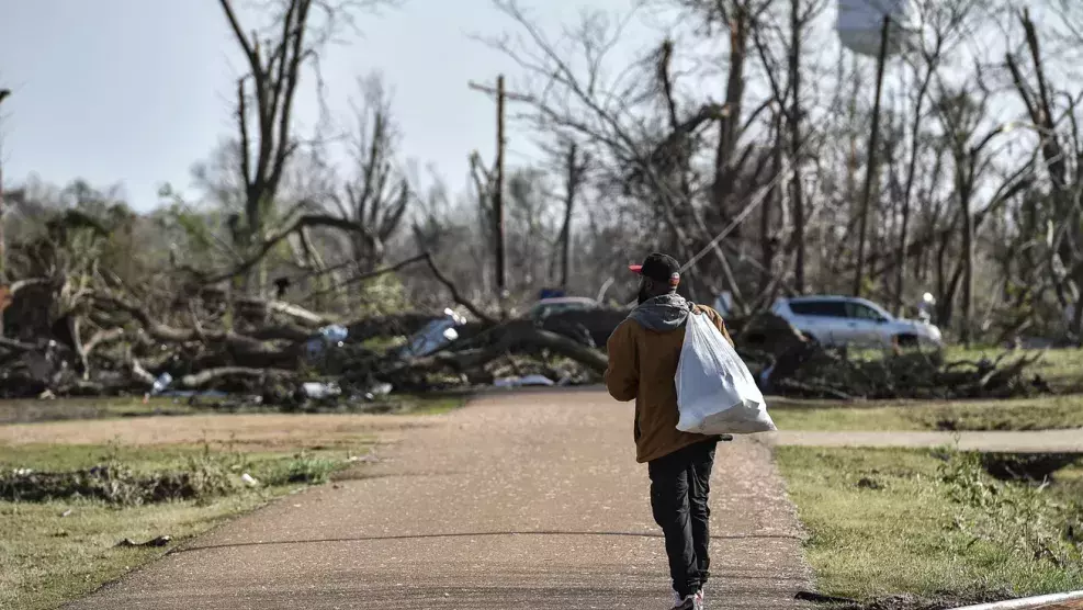 Terry York, a Silver City, Miss., resident, walks through a damaged neighborhood with a small bag of personal belongings, Saturday, March 25, 2023, after a deadly tornado ripped through the area the night before.