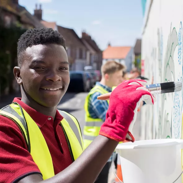 Young Black Male Painting Wall with Group