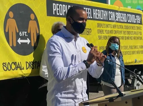 Josh Harris, black man in a mask standing at podium