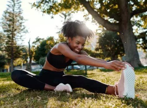 Athletic Young Black Female Stretching Legs Outside