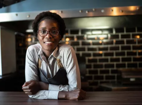 Young Female with Apron in Industrial Kitchen - Smiling