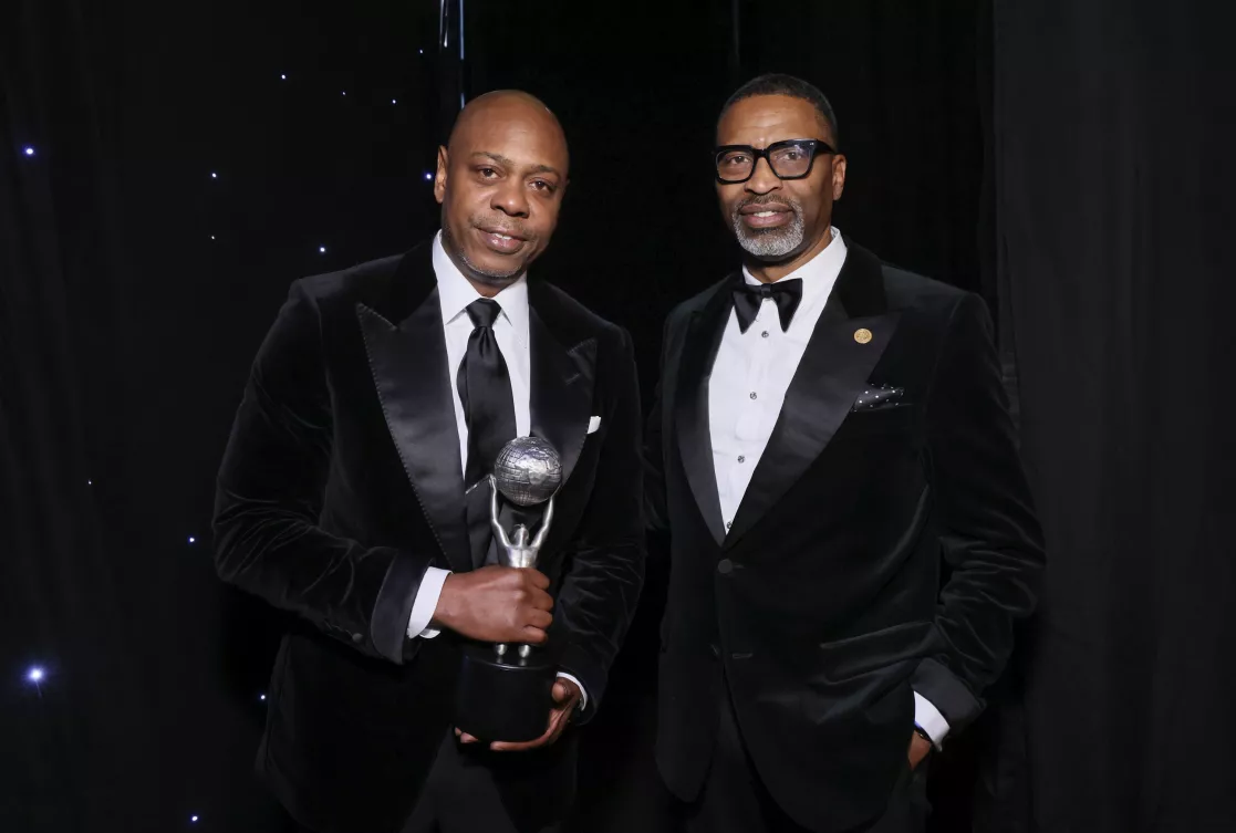 Comedian Dave Chappelle poses with his trophy next to NAACP President and CEO Derrick Johnson at the 56th NAACP Image Awards.