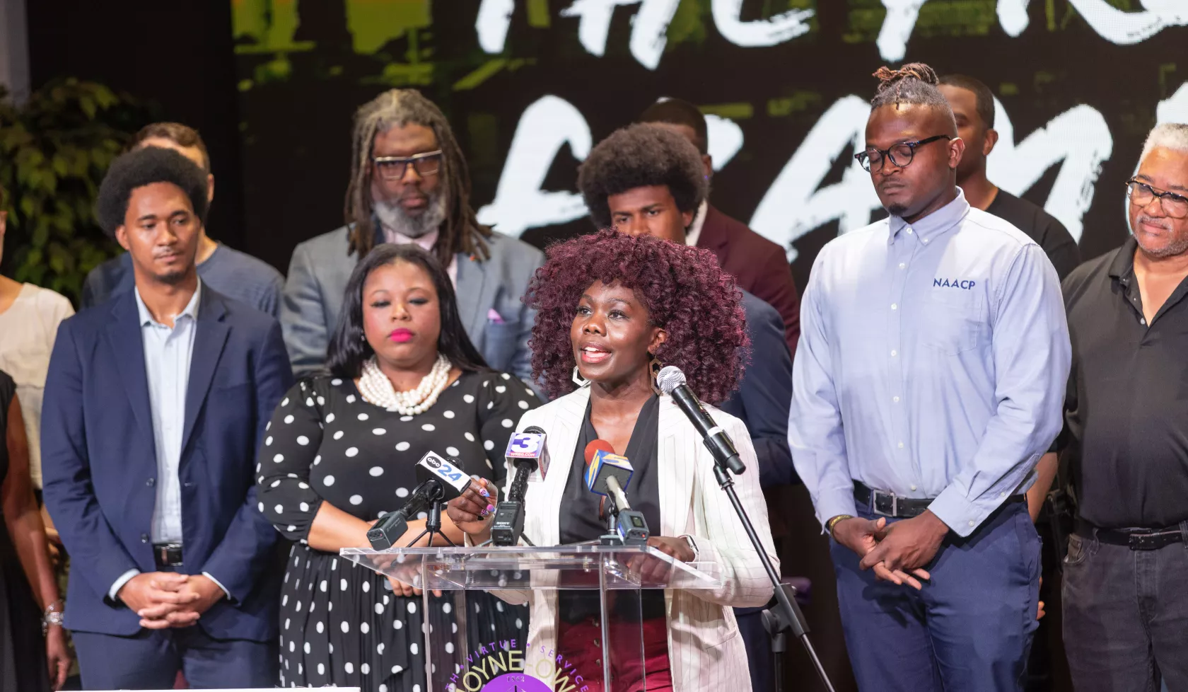 People of color standing at a podium for a press conference