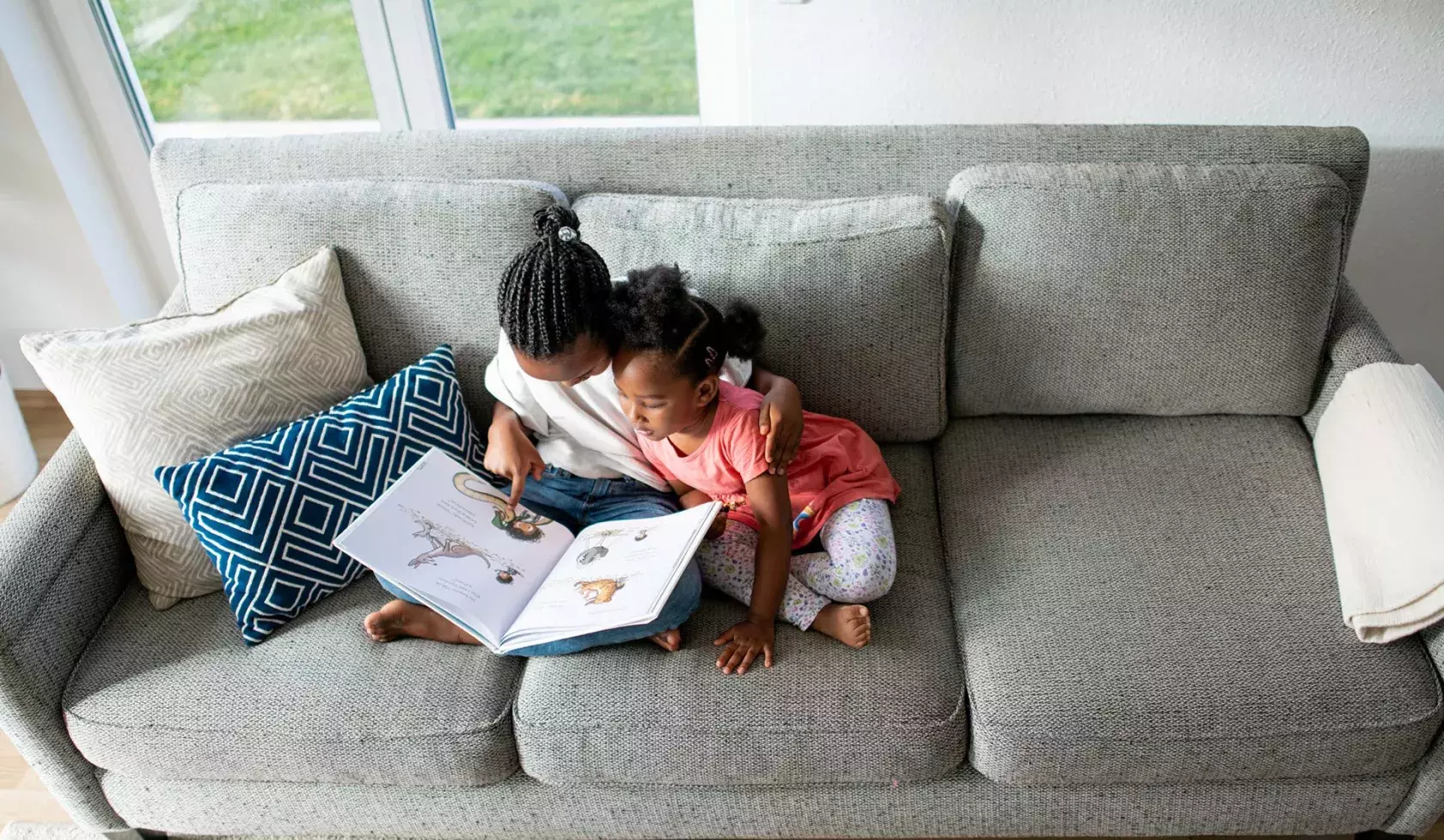 Young Black Female Children Reading Together on Couch