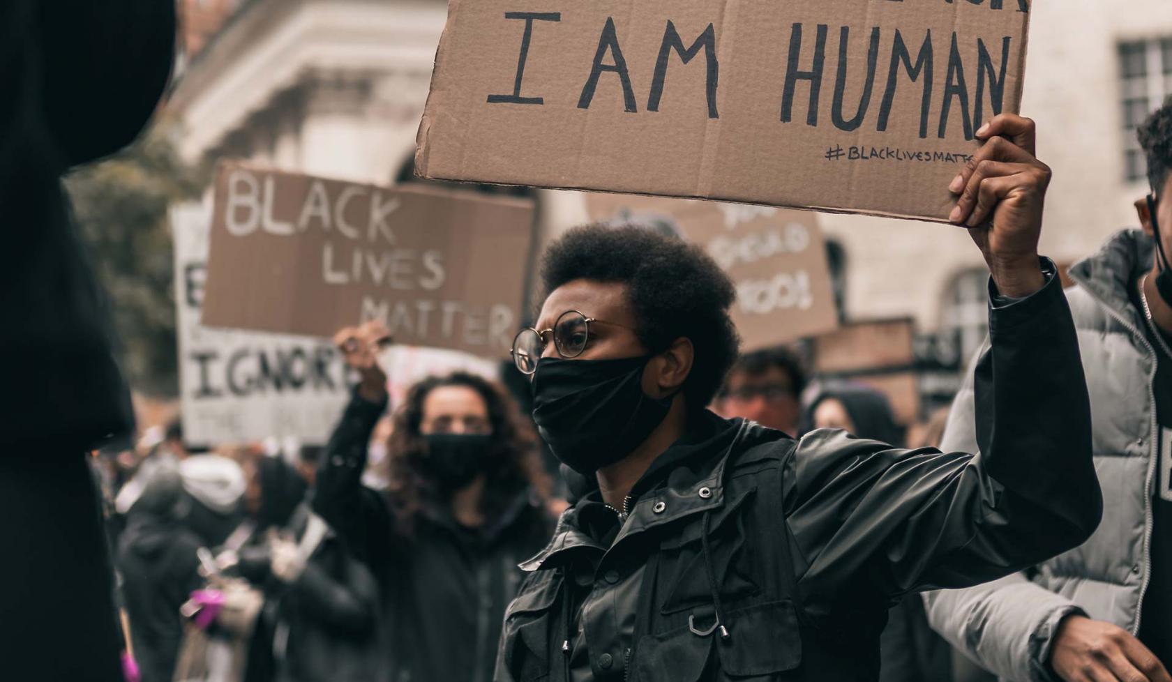 Black Male - Outdoors - at protest or rally - holding sign - wearing face mask