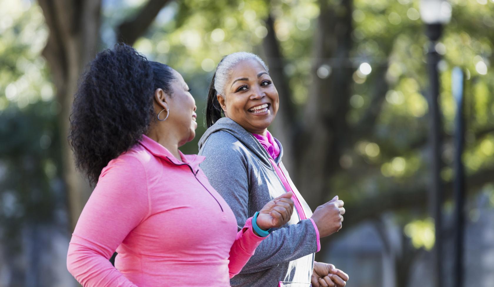 Two Black Women Smiling at Each Other While Enjoying a Power Walk Outside