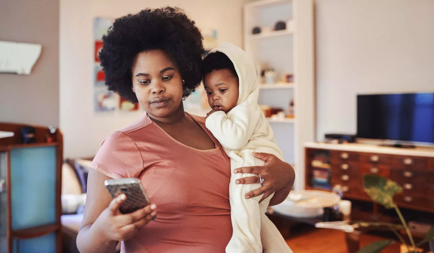 Black Female Holding Baby and Checking iPhone