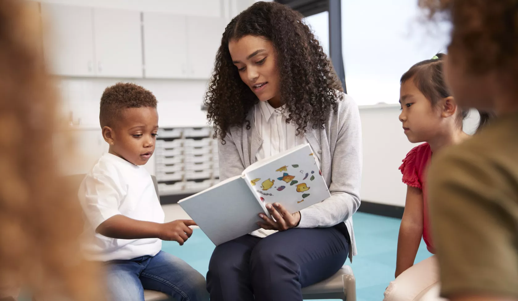 Teacher Reading a Book to a Seated Group of Young Children