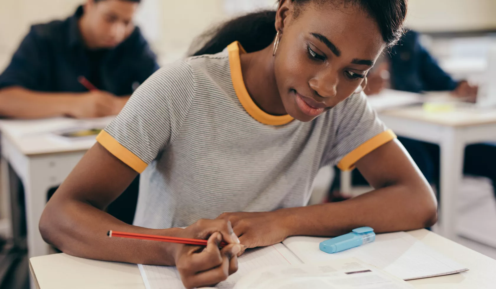 Black Student Sitting at Classroom Desk Doing Coursework