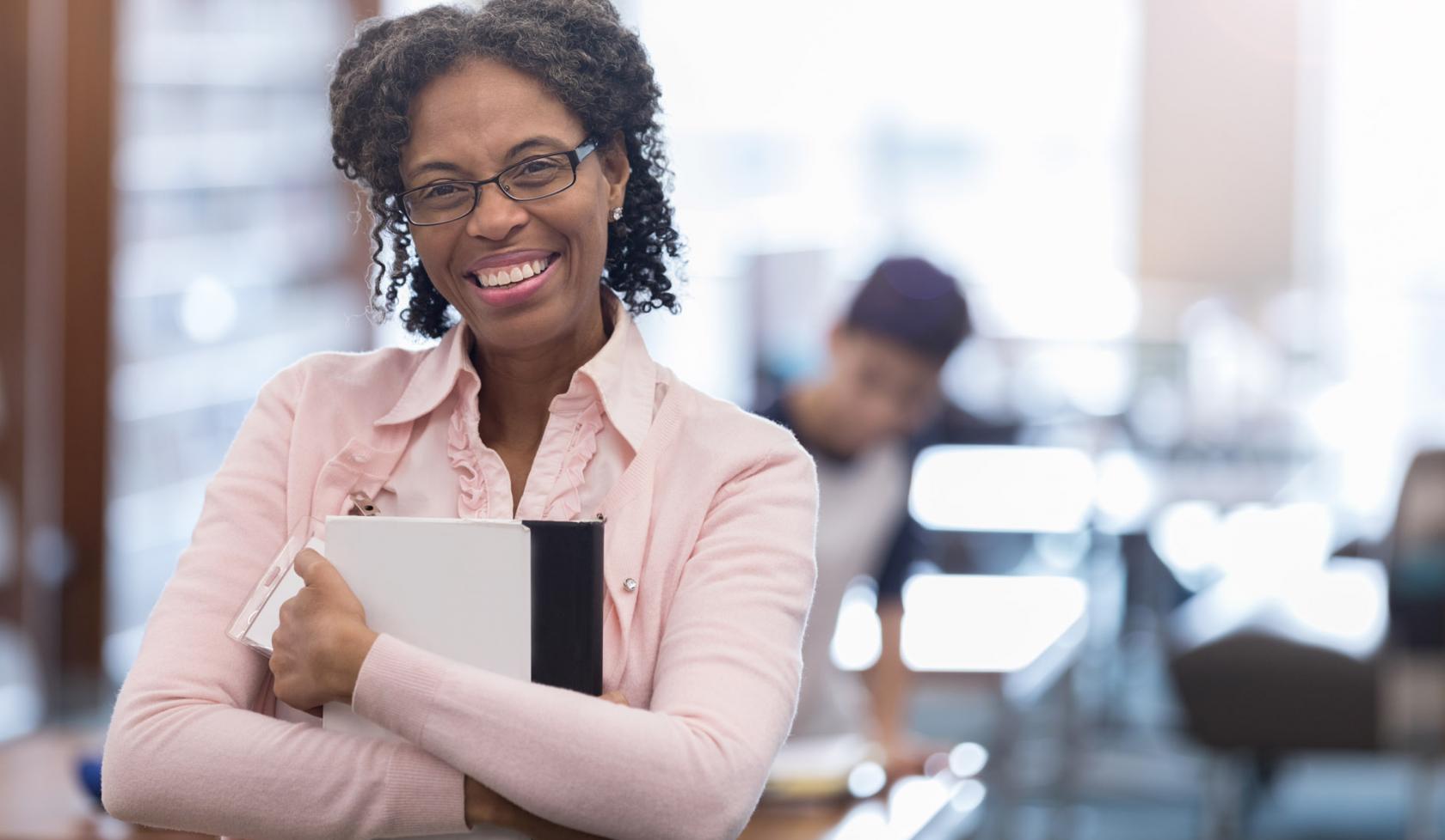 Close-up Black Female Professional Smiling at Camera While Holding Paperwork