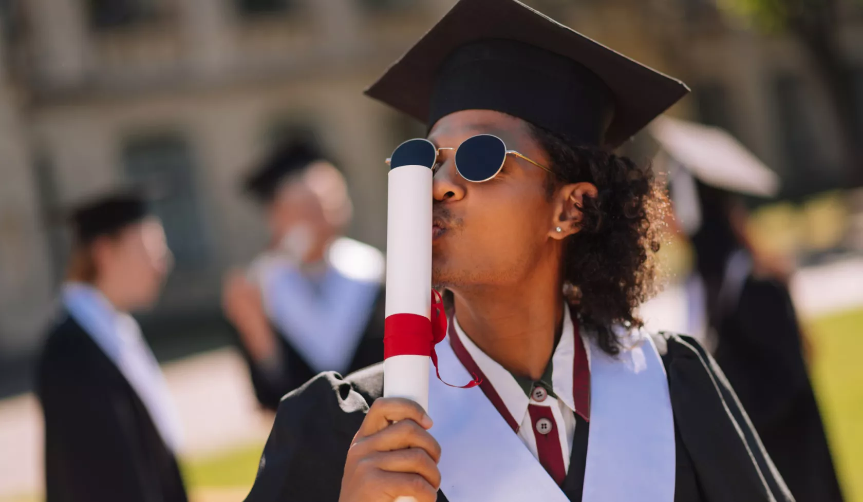 Black Graduate Kissing Rolled-Up Diploma - Outdoors