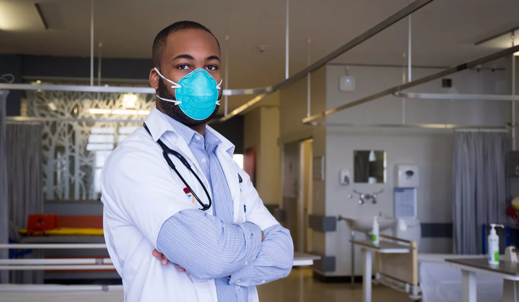 Masked Doctor with Crossed Arms inside Hospital