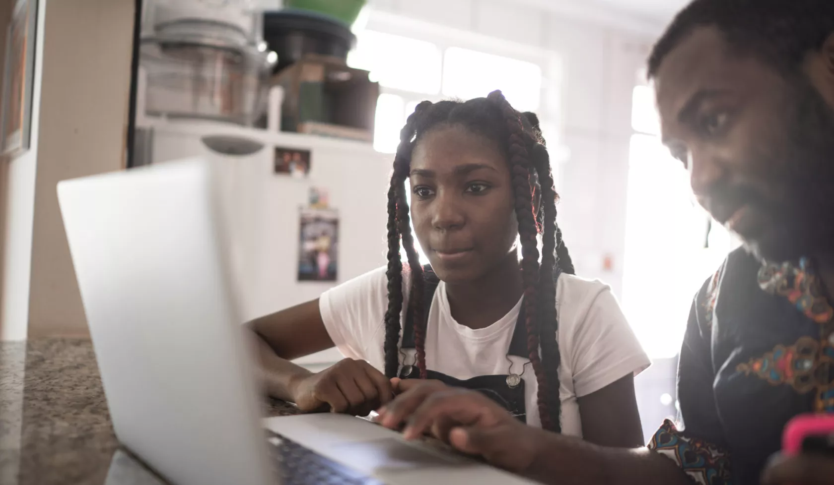 Parent and Young Teen Looking at Laptop Together