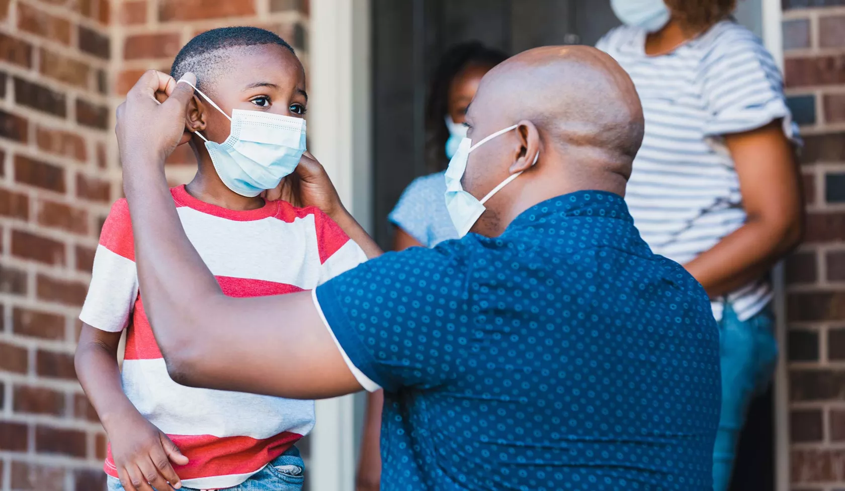 Black Man Helping a Child Put on a Mask