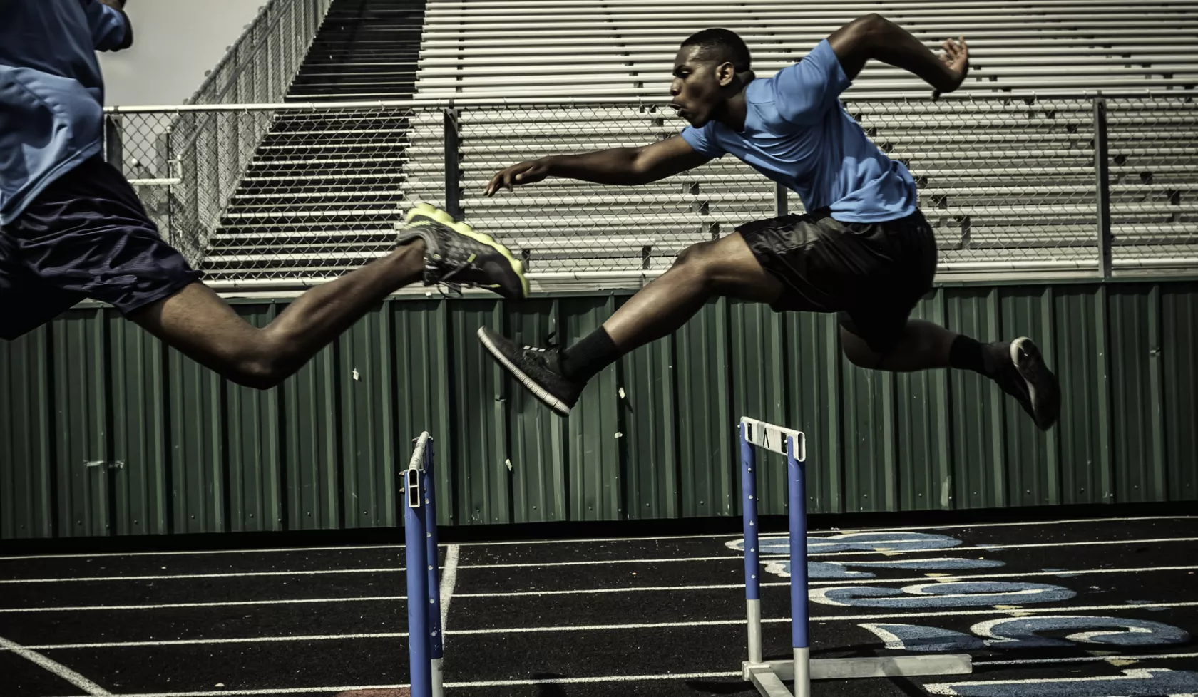 Black Athlete Jumping Over Hurdles on Track