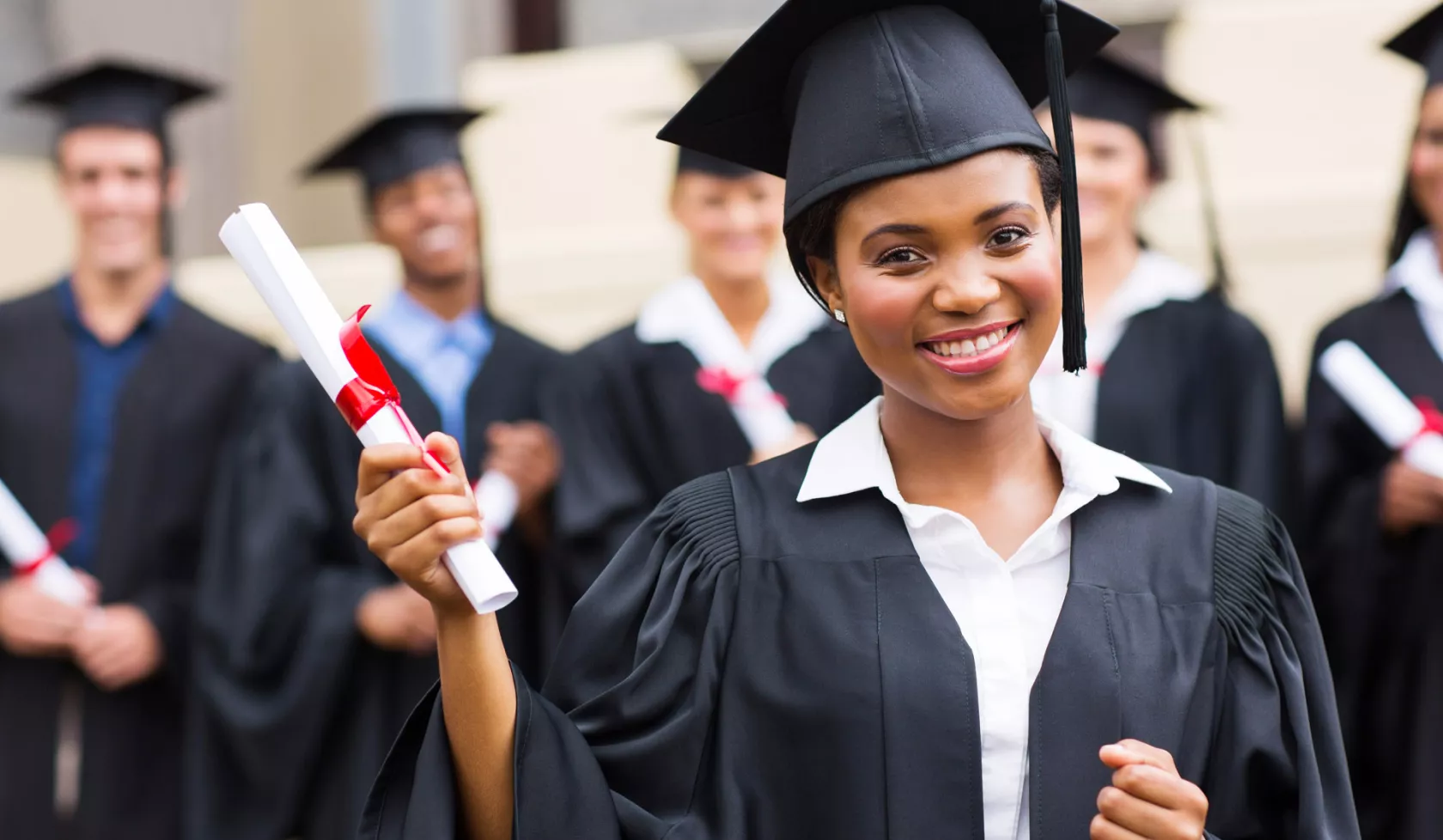 Smiling Female Graduate Wearing Cap and Gown Holding Diploma