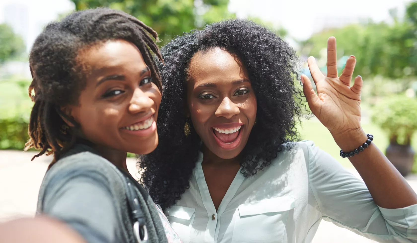 Two Grinning Black Women Taking a Selfie Together Outside