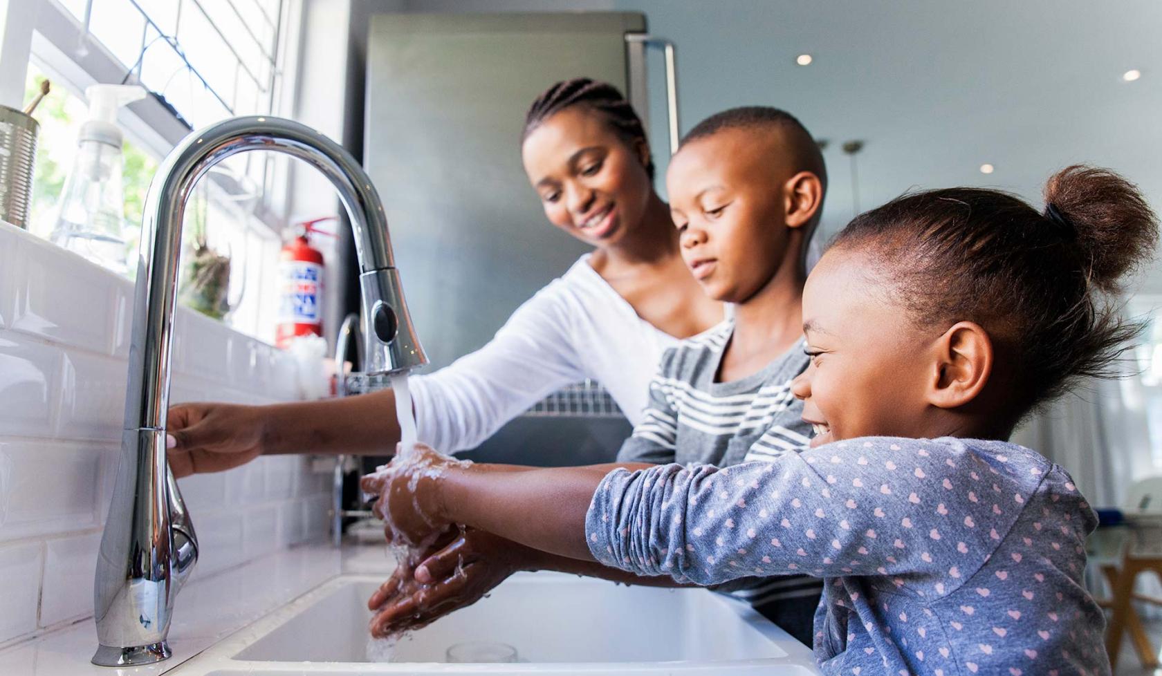 Black Mother with Two Children in Front of Kitchen Sink - Smiling