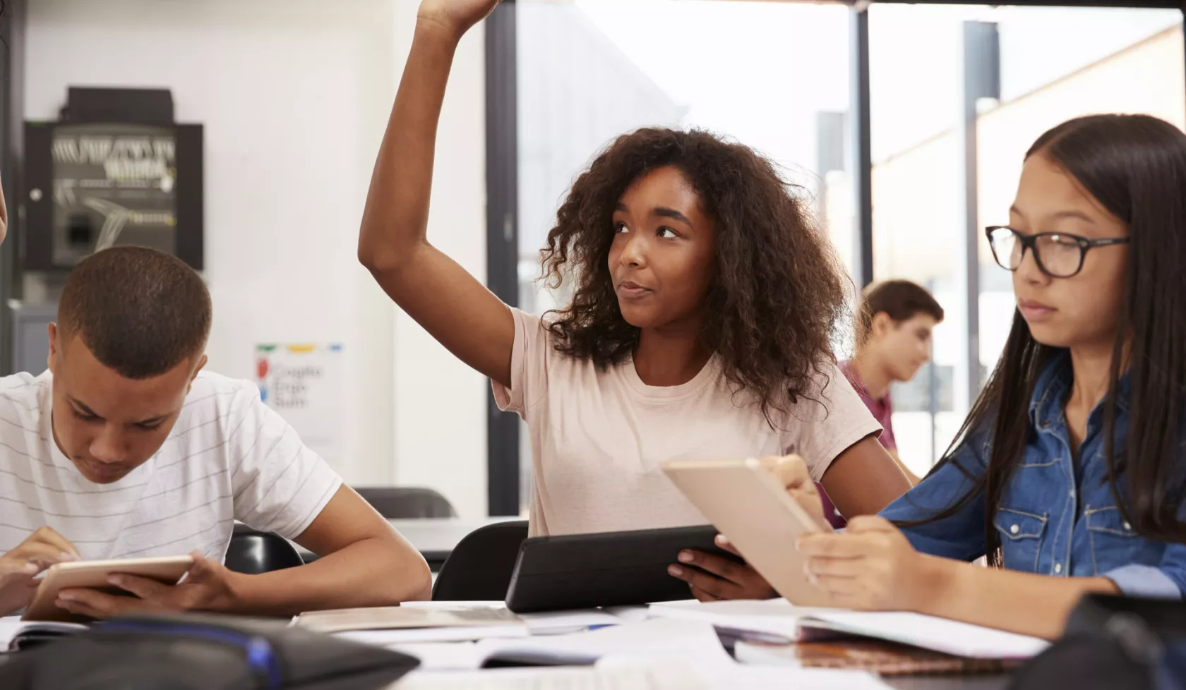 Black Student Sitting with Peers and Raising Hand in the Air