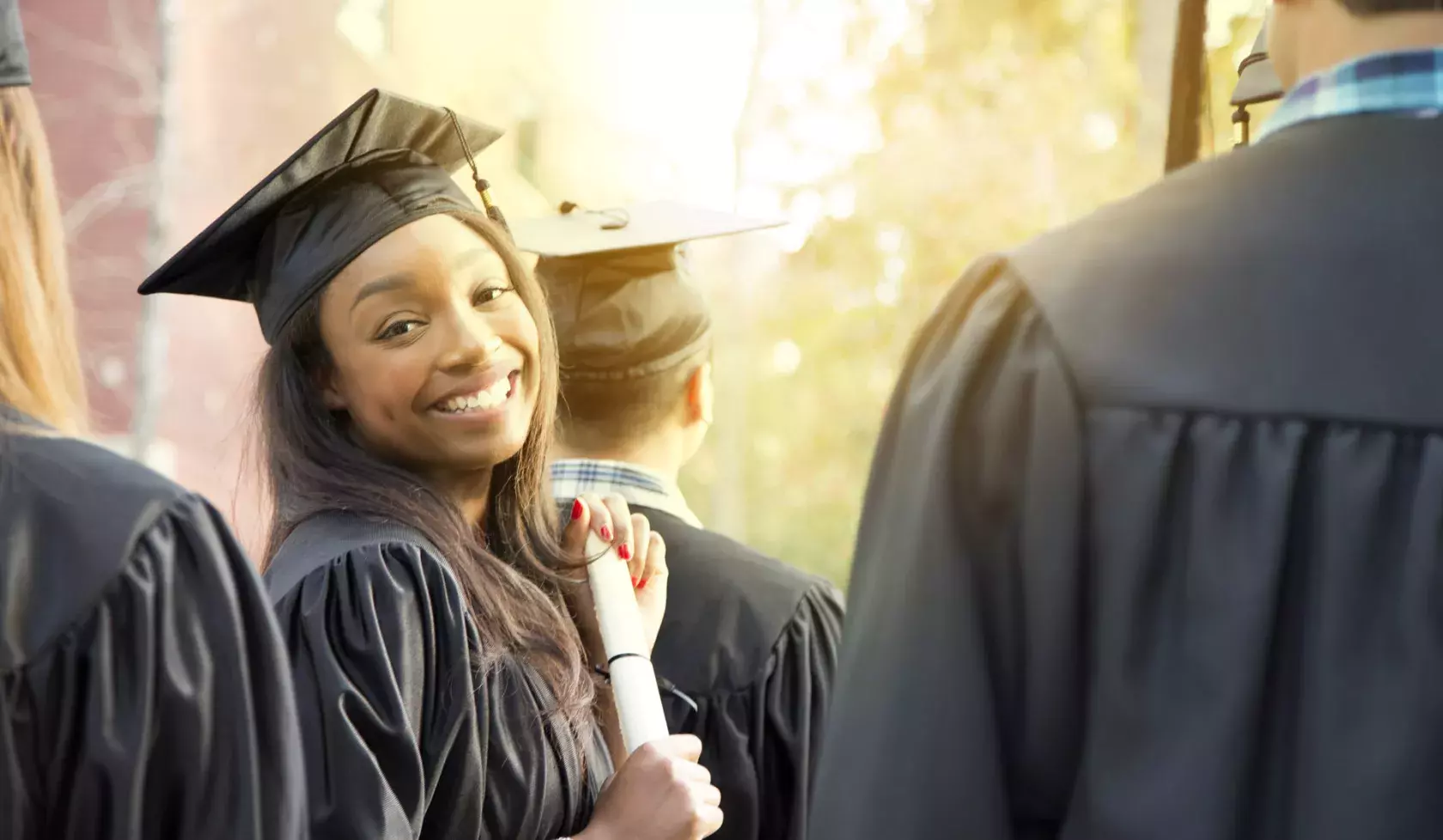 Close-up of Black Female Graduate Smiling at Camera Amongst Group of Fellow Students