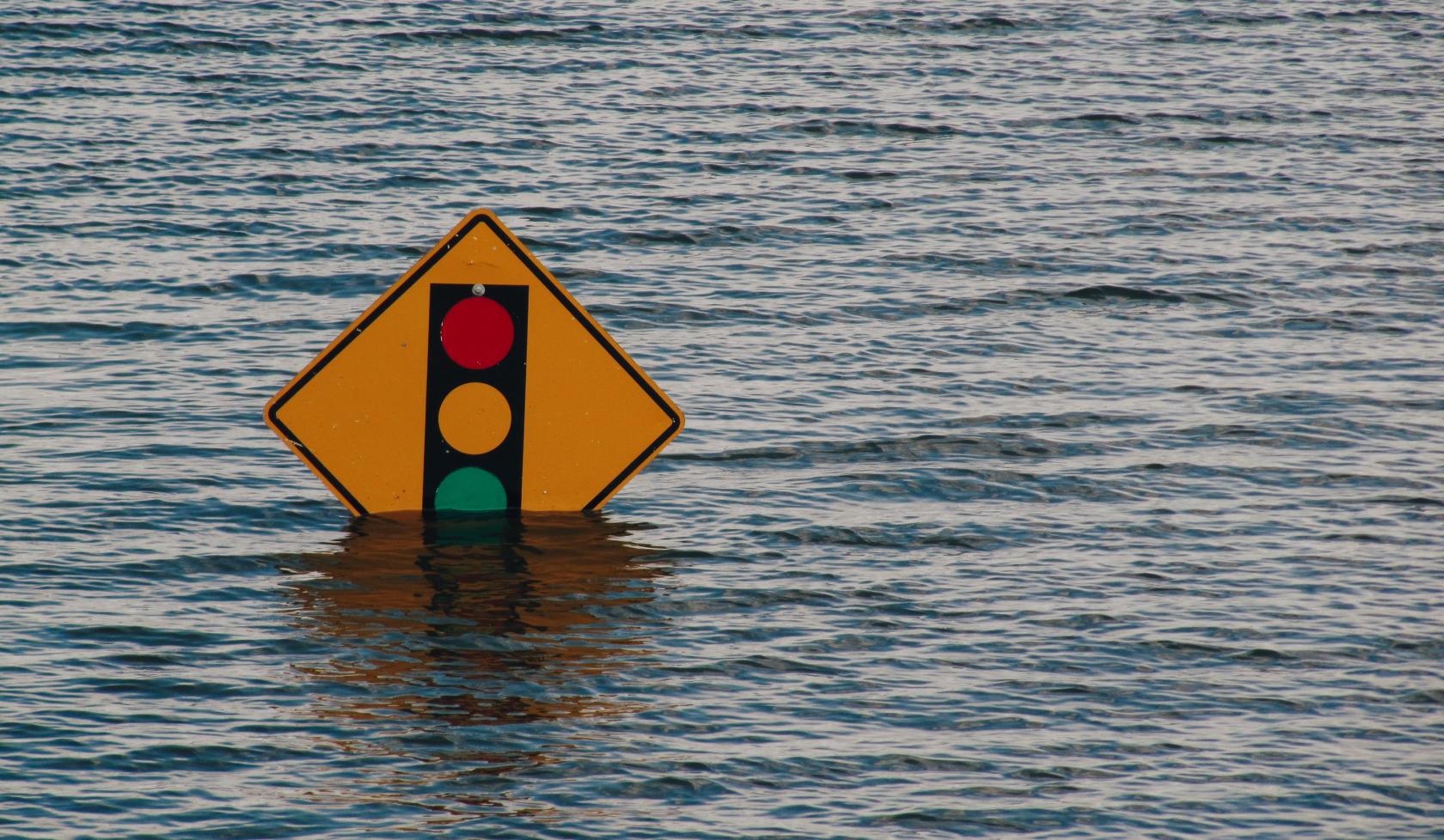 Yellow traffic sign partially submerged in floodwater