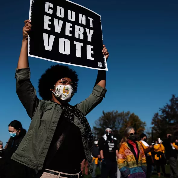 Black Female holding Voting Sign - Group in background - wearing face mask