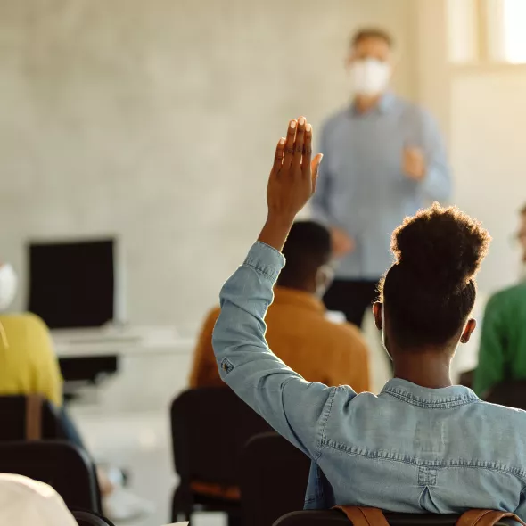 Girl with raised hand in classroom