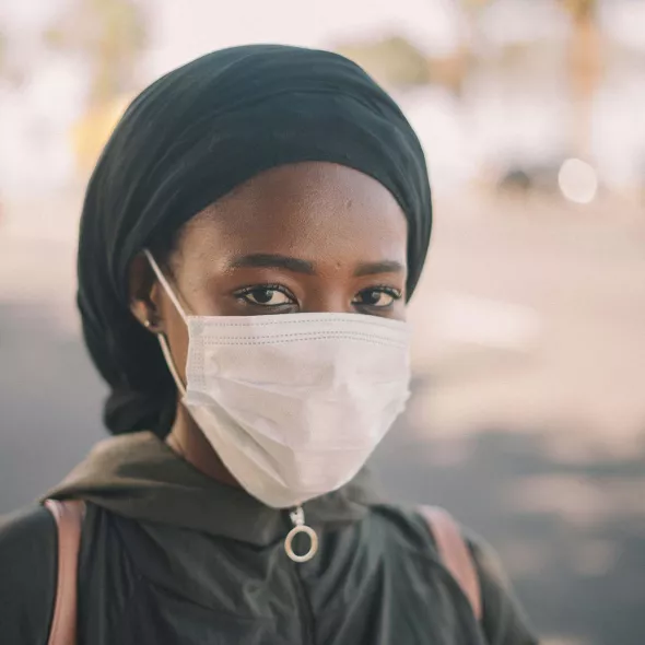 Woman in mask looking at camera with a serious expression