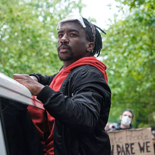 Black Male Outdoors - at protest or rally - group in background