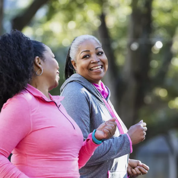 Two Black Women Smiling at Each Other While Enjoying a Power Walk Outside