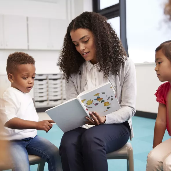 Teacher Reading a Book to a Seated Group of Young Children