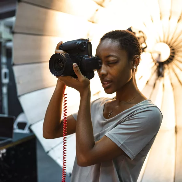 Photographer Holding Camera to Face inside Photography Studio