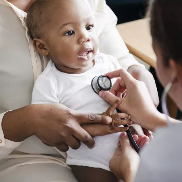 Baby with Doctor's Stethoscope on Chest at Medical Appointment