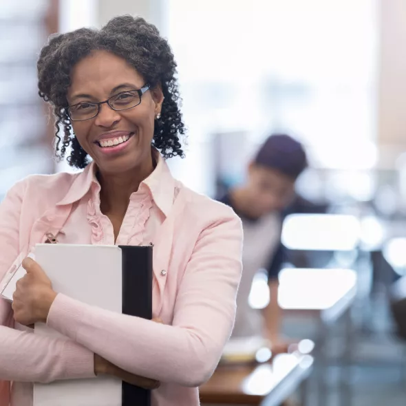 Close-up Black Female Professional Smiling at Camera While Holding Paperwork