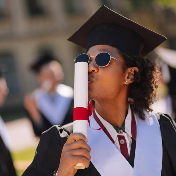 Black Graduate Kissing Rolled-Up Diploma - Outdoors