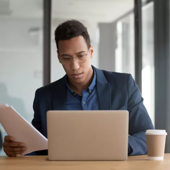 Black Male Professional Focused on Laptop and Paperwork