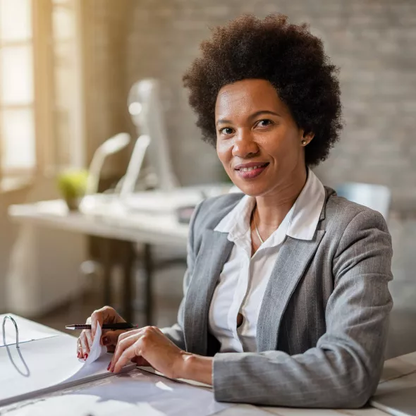 Professional Smiling at Camera While Working at Desk