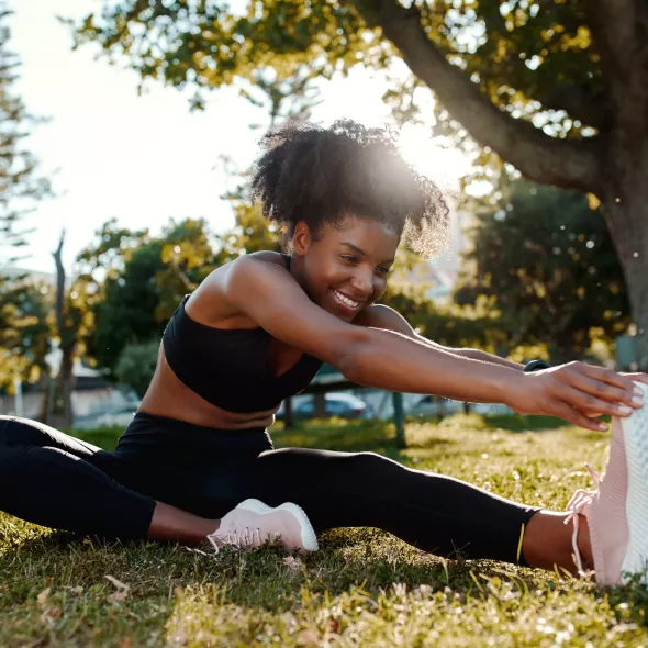 Athletic Young Black Female Stretching Legs Outside