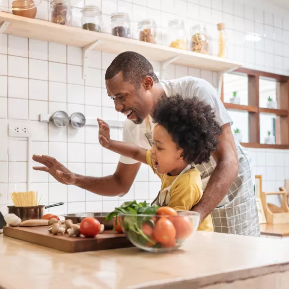 Father and Child Cooking in Kitchen and Waving at Tablet