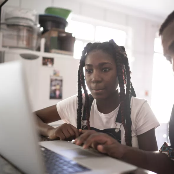 Parent and Young Teen Looking at Laptop Together