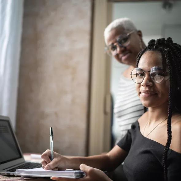 Black Woman with Laptop and Supportive Person Smiling at Camera