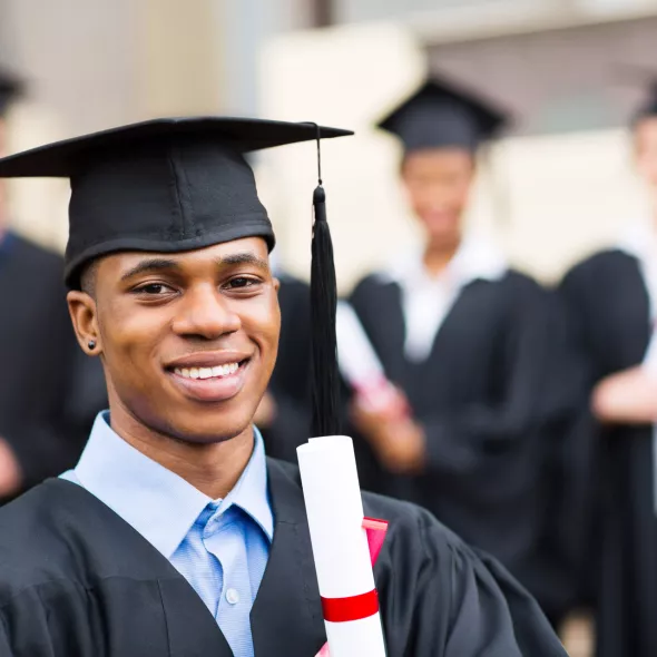 Black Male Graduate Smiling at Camera and Holding Diploma