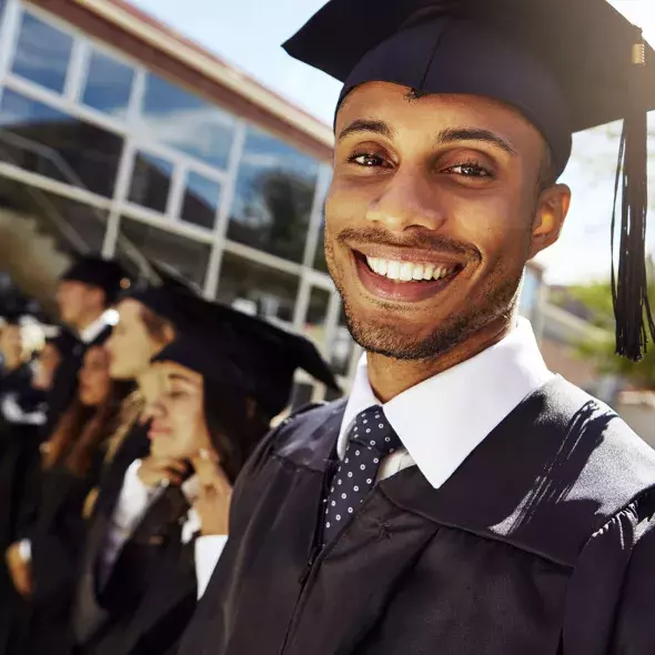 Close-up Male Graduate with Cap and Gown Smiling at Camera