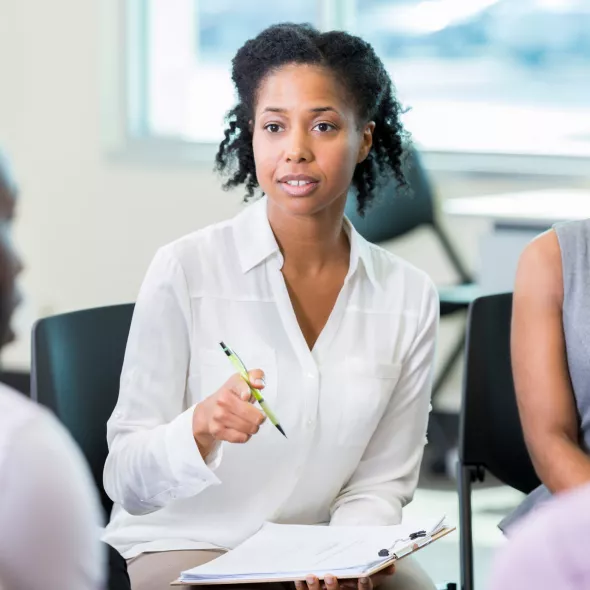 Female Professional Speaking to a Seated Group of People