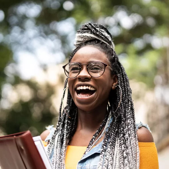 Joyous Young Black Woman Holding Books - Outdoors