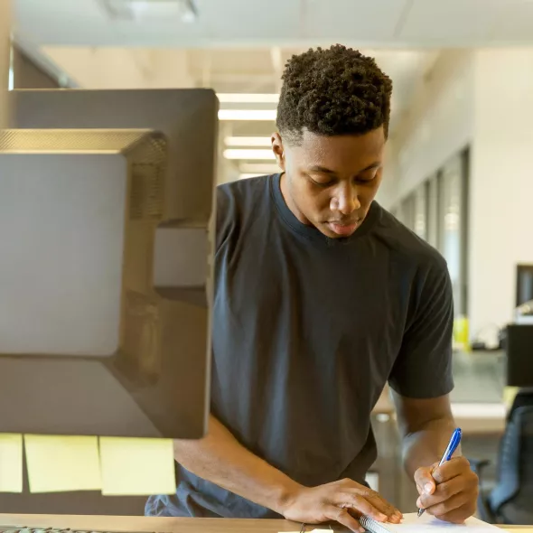 Young Black Male - Solo - standing working at computer - classroom setting