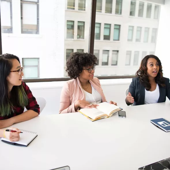 Three Young Females Working Together at an Office Table
