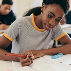 Black Student Sitting at Classroom Desk Doing Coursework