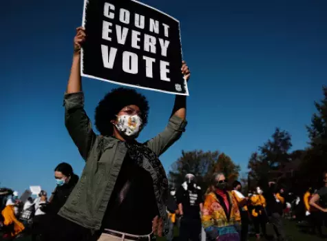 Black Female holding Voting Sign - Group in background - wearing face mask